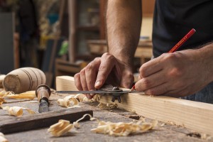 Hand of a carpenter taking measurement of a wooden plank